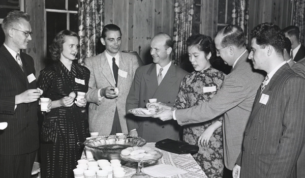 Several people stading around a punch bowl at a party